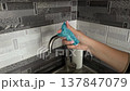 Hand squeezing dishwashing sponge with detergent foam near kitchen sink faucet closeup cleaning routine hygiene concept household chores washing dishes domestic sanitation lifestyle 137847079