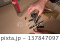 Metal screws spilling from plastic container onto wooden table closeup hardware fasteners scattered on work surface construction repair tools workshop concept DIY materials preparation and sorting 137847097
