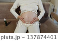 A pregnant woman's hands and abdomen during body care. A pregnant woman's belly in her seventh month. A young Caucasian woman in late pregnancy, stroking her abdomen, massaging the baby in the womb. 137874401