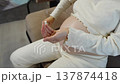 Seventh month of pregnancy. Pregnant woman squeezes cream from tube and applies lotion to belly to treat dry skin. Close-up of hands applying cream to belly to prevent stretch marks in late pregnancy. 137874418