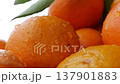 Pile of fresh mandarins displayed with other citrus and tropical fruits visible behind. Citrus 137901883