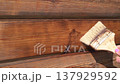 A woman covers the wall of a wooden house with protective oil. 137929592