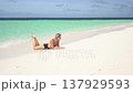 A young woman lies alone and sunbathes on a sandy sea beach on a tropical island. 137929593