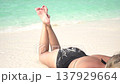 Happy young woman sunbathing in a swimsuit on a sandy beach on a tropical island. 137929664