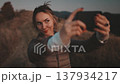 Woman making evening selfie in autumn mountain field. Caucasian girl holding the phone in her hands and recording the content. Travel, tourism, holiday, trekking, hiking, active lifestyle. Slow motion 137934217