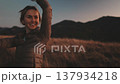 A woman celebrates in the Carpathian mountains at dusk, surrounded by stunning landscapes and enjoying her time in nature. 137934218