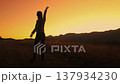 A woman stands in silhouette against a vibrant sunset while exploring the Carpathian Mountains, capturing a moment of joy and adventure. 137934230