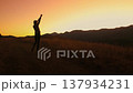 A woman stands on a mountain pathway, enjoying the breathtaking sunset views in the Carpathian Mountains, capturing a moment of joy and tranquility. 137934231