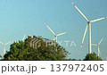 Several wind turbines rotate across an open landscape filmed while driving through wide terrain 137972405