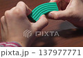 Child sculpting clay with fingers. Soft plasticine in tiny hands. Hands of a kid with soft modeling clay. A child holds turquoise plasticine in his hands. Tiny fingers pressing soft clay 137977771