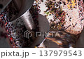 Detailed shot of a rotating mechanism crushing ripe grape berries for juice extraction. Automated agricultural production in operation. 137979543
