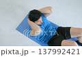 Top view of motivated active sporty fitness man practicing sit-ups exercise, flexing abs, strengthening back and hip muscles while doing sports training at home. 137992421