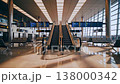 Empty airport escalator under departure boards, polished floors reflecting light, rows of seats, large windows, digital flight screens and spacious modern architecture creating calm 138000342