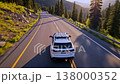 White SUV driving mountain road bathed in warm golden light, winding through pine forest and rocky slopes, guardraillined highway, cinematic aerial follow shot, serene solitude 138000352