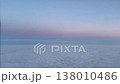 Serene aerial view from an airplane window over a soft cloud blanket and pastel blue sky at twilight. Minimal horizon scene with copy space, ideal for travel and aviation concepts. 138010486