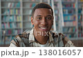 Smiling African American man student toothy smile looking at camera university library happy male guy learner studying education bookshelf academic bookworm intelligent smart reader college knowledge 138016057