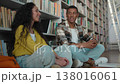 African American man Indian Hispanic woman talking chatting sitting on library floor multiethnic students studying female male classmates university college conversation reading club education books 138016061