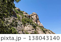 Walking in the mountains of Montserrat in Spain in summer. Panorama of mountain peaks and green plants against the blue sky. Trails for active recreation 138043140
