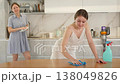 Positive young girl cleaning the surface of table, mother drying dishes with towel in the kitchen 138049826
