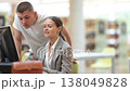 Guy helps a female student find information on the internet using a computer in a university library 138049828