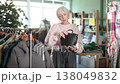 Elderly woman carefully selects fashionable handbag in a clothing store 138049832