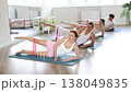 Slender young men and women practicing leg lift with resistance band on knees lying on the side in pilates studio 138049835