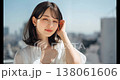 A young woman with bobbed hair is blown by the wind, against a backdrop of a blue sky and a city. 138061606
