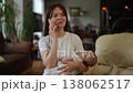 Multitasking mother holding a sleeping baby while talking on the smartphone 138062517