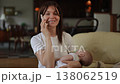 Young mother holding her sleeping baby while talking on the phone 138062519