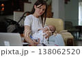 Young mother multitasking holding a sleeping baby while working from home 138062520