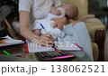 Mother juggling work and family life holding newborn baby 138062521