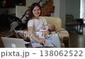 Mother juggling work and childcare holding sleeping baby 138062522