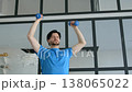 Determined handsome sporty fit man practicing dumbbell standing shoulder press, improving strength in chest, shoulders, deltoids, and triceps during indoor sports training 138065022