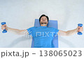 Overhead view of active fit man in sportswear lying on yoga mat, practicing dumbbell chest fly exercise, increasing shoulder and core strength while working out at home. 138065023