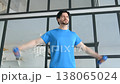 Motivated healthy lifestyle fitness man in sportswear practicing dumbbell lateral raise exercise, strengthening and toning shoulder and upper body muscles in domestic room. 138065024