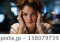 A contemplative young woman with curly hair expressing deep thought and introspection in a modern workspace, portraying a moment of focus amidst distractions. 138079739