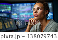 Focused professional woman in glasses contemplating data analytics in a modern workspace with digital screens displaying various charts and graphs. 138079743