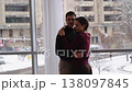 Couple embraces indoors while snow falls outside in a cozy setting 138097845