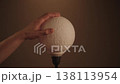 Human hand touching spherical night lamp that resembles moon surface, turning light on and off and changing its warm and cool color temperature, closeup. Shooting in slow motion. 138113954