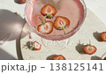 Pink strawberry cocktail with ice and sugar rim on marble tray. Fresh halved berries floating in sparkling rose drink in bright natural sunlight with shadows. 138125141