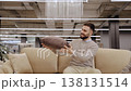 Happy man choosing pillows for sofa in home decor store 138131514