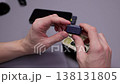 Close-up hands of newsman examining modern wireless microphone system, opening charging case, checking transmitter and accessories before connecting to smartphone for recording, close-up, slow motion. 138131805