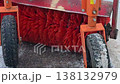 Rotating red cylindrical brushes of a street sweeper machine clean the asphalt road surface during the cold winter season. 138132979