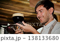 Close up of handsome young male brewer in apron tasting fresh dark beer. Tasting fresh brewed beer. Beer production concept. Brewing 138133680