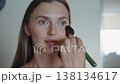 A face of a smiling woman applying a makeup powder with a brush. Portrait, cosmetic product and powder of model, skin foundation and facial beauty. 138134617