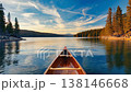 Wooden canoe sailing on calm lake at sunset with forest and mountains 138146668