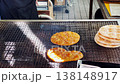 A hand is using tongs to flip crackers over a traditional hot charcoal grill in the Oshino Hakkai village of Yamanashi, Japan. 138148917