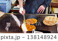 A hand is using tongs to flip crackers over a traditional hot charcoal grill in the Oshino Hakkai village of Yamanashi, Japan. 138148924