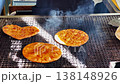 A hand is using tongs to flip crackers over a traditional hot charcoal grill in the Oshino Hakkai village of Yamanashi, Japan. 138148926