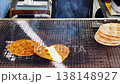 A hand is using tongs to flip crackers over a traditional hot charcoal grill in the Oshino Hakkai village of Yamanashi, Japan. 138148927